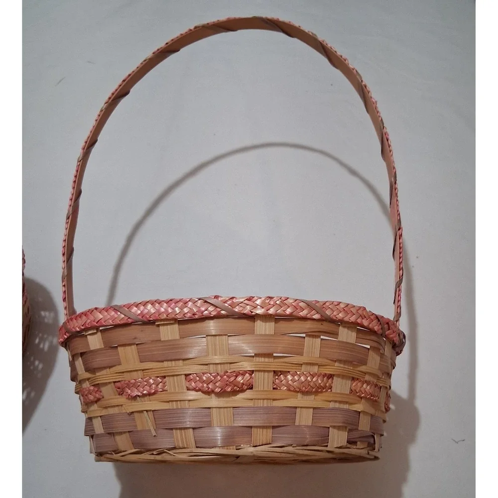 Two vintage woven bamboo baskets with‎ tall handles and pink accenting.